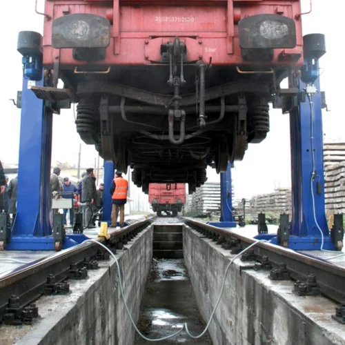 Zvednutý vagón nad montážní jámou nádraží